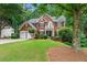 Brick home boasts a manicured lawn, mature trees, and a convenient two-car garage at 1115 Ballington Dr, Cumming, GA 30041