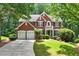 Charming two-story brick home with a manicured lawn, mature trees, and a two-car garage at 1115 Ballington Dr, Cumming, GA 30041