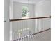 Bright hallway featuring wood railing and a large window overlooking the front yard at 1115 Ballington Dr, Cumming, GA 30041
