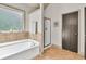 Bathroom with a tiled tub, a walk-in shower, and a brown door at 2525 Well Springs Dr, Buford, GA 30519