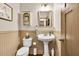 Charming half bathroom with wainscoting, pedestal sink, decorative mirror, and neutral tones at 2525 Well Springs Dr, Buford, GA 30519