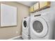 Well-equipped laundry room with modern washer, dryer, storage shelf, and stylish gray tile floor at 5769 Tillman Way, Powder Springs, GA 30127