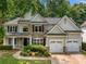 Charming home featuring stone accents, a well-manicured lawn, an attached two-car garage, and a welcoming front porch at 1205 Compass Pointe Xing, Alpharetta, GA 30005