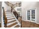 Inviting foyer with a staircase featuring a wrought iron railing and access to other rooms through glass panel doors at 1205 Compass Pointe Xing, Alpharetta, GA 30005