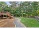 Spacious backyard with a stone pathway, wooden deck, fire pit, and mature trees, creating a private oasis at 112 Birchwood Pass, Canton, GA 30114