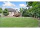 Expansive backyard with lush green lawn, mature trees, wooden deck, and a charming fire pit area at 112 Birchwood Pass, Canton, GA 30114