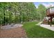 Manicured backyard with a stone fire pit, lush green grass, and mature trees, perfect for outdoor entertaining at 112 Birchwood Pass, Canton, GA 30114