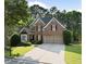 Brick home with a well-manicured front lawn, mature trees, and a two-car garage offering curb appeal at 112 Birchwood Pass, Canton, GA 30114