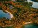 Scenic aerial view of waterfront property surrounded by lush, fall-colored trees at 6520 Pond View Dr, Cumming, GA 30028