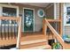 Inviting front porch with wood railing, steps, and a glass front door with unique windows at 141 Mills Creek Path, Hiram, GA 30141