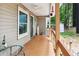Spacious side porch with wood floors and railing, with flag accent and views of the lush yard at 141 Mills Creek Path, Hiram, GA 30141