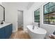 Modern bathroom featuring a soaking tub, blue vanity, and natural light at 3345 Bomar Rd, Douglasville, GA 30135