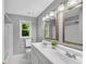 Bright bathroom featuring a double sink vanity, framed mirrors, and a window overlooking the greenery at 3402 Johnson Ferry Rd, Roswell, GA 30075