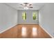 Spacious bedroom features hardwood floors, neutral paint, a ceiling fan, and natural light from two windows at 3402 Johnson Ferry Rd, Roswell, GA 30075
