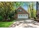 Attached garage with a white door, lush landscaping, and plenty of parking space at 3402 Johnson Ferry Rd, Roswell, GA 30075