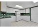 A kitchen featuring white cabinets, green marble counters and backsplash, and white tile flooring at 3402 Johnson Ferry Rd, Roswell, GA 30075