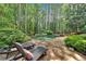 Secluded backyard featuring a stone patio and lounge chairs surrounding a freeform pool nestled in a wooded landscape at 4012 Ironhill Ln, Woodstock, GA 30189