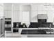 Modern kitchen with black marble countertops, white cabinetry, and stainless steel appliances at 4825 Gadwall Way, Cumming, GA 30028