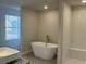 A luxurious bathroom displays a sleek, standalone tub and a vanity with modern fixtures and tile surround at 5381 Tolar Rd, South Fulton, GA 30213