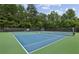 Outdoor tennis court with well maintained surface, surrounded by lush greenery at 10300 Medridge Cir, Johns Creek, GA 30022