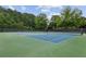 Outdoor tennis court surrounded by lush greenery with well maintained surface at 10300 Medridge Cir, Johns Creek, GA 30022