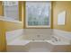 Soaking tub surrounded by tile, a large window with natural light, and neutral tones for a spa-like experience at 1951 Chambers Rd, Mcdonough, GA 30253