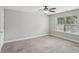 This bedroom features a window with a ceiling fan and neutral walls and carpet flooring at 4546 Water Mill Dr, Buford, GA 30519