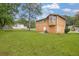 Back of the home with a large, well-maintained lawn, mature trees, and a cozy patio area at 5653 Bradley Cir, Lithonia, GA 30038