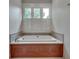 Bright bathroom featuring a soaking tub beneath a window with white shutters, tile backsplash, and wood cabinetry at 114 Trinity Hollow Dr, Canton, GA 30115
