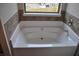 Bright white bathtub with tile backsplash set below a window with a neighborhood view at 1530 Horseshoe Creek Ln, Cumming, GA 30041