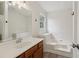 Bright bathroom featuring a white vanity, mirror, and soaking tub at 3970 Genoa Ct, Duluth, GA 30096