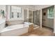 Updated bathroom featuring a soaking tub, glass-enclosed shower, tiled walls, and a bright window at 5105 Kings Common Way, Cumming, GA 30040