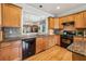 Granite countertops and stainless steel dishwasher in an open kitchen with warm wood cabinetry at 5105 Kings Common Way, Cumming, GA 30040
