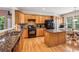 Bright kitchen with wooden cabinets, island, and black appliances, adjacent to a breakfast nook at 5105 Kings Common Way, Cumming, GA 30040