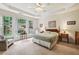 Bright main bedroom with large windows, tray ceiling, and cozy seating area overlooking the landscaped backyard at 5105 Kings Common Way, Cumming, GA 30040