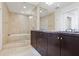Bathroom with dual sink vanity, dark cabinetry, glass-enclosed shower, and bathtub with neutral tile at 3325 Piedmont Ne Rd # 2104, Atlanta, GA 30305