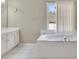 Bright bathroom showcasing a soaking tub, a large window with white blinds, and double sinks on a white vanity at 6302 Manassas Nw Pass, Acworth, GA 30101