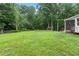 Expansive backyard featuring lush lawn, mature trees, a custom playhouse, and storage shed at 2060 Candlewood Ne Ct, Marietta, GA 30066