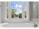 Close-up of a large window over soaking tub with chrome fixtures and views of the backyard at 10865 Misty Moon Ct, Alpharetta, GA 30022