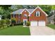 Attractive two-story brick home with an attached two-car garage, manicured lawn, and shade trees at 10865 Misty Moon Ct, Alpharetta, GA 30022