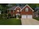 Beautiful brick home with a two-car garage, well-manicured lawn, mature trees, and landscaping at 10865 Misty Moon Ct, Alpharetta, GA 30022