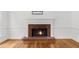Close-up of a brick fireplace with a white mantle and hardwood flooring in a bright living room at 10865 Misty Moon Ct, Alpharetta, GA 30022