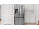 Stainless steel refrigerator in a kitchen with white cabinets and light tile floors at 10865 Misty Moon Ct, Alpharetta, GA 30022