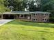 Charming brick home featuring a well-manicured lawn, covered porch, and mature trees at 1850 Donald Dr, Marietta, GA 30062