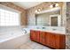 Bathroom with a double vanity, soaking tub and large mirror at 65 Orchard Dr, Covington, GA 30014