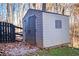 Outdoor storage shed in backyard with double doors and window and surrounded by trees and a black fence at 126 Laguna Springs Dr, Woodstock, GA 30188