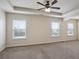 Large carpeted bedroom with tray ceiling, ceiling fan, and three windows at 203 Creek View Ln, Acworth, GA 30102