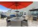 Charming backyard patio with dining set, grill, and comfortable seating under a vibrant orange umbrella at 11684 Stovall Pl, Hampton, GA 30228