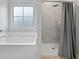 A bright bathroom featuring a soaking tub, and a tiled shower with a glass door at 11684 Stovall Place Pl, Hampton, GA 30228