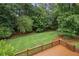 Green backyard bordered by mature trees and a wooden deck, enhancing outdoor privacy and scenic view at 1338 Nonie Way, Marietta, GA 30062